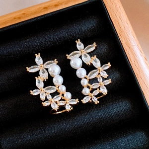 Macro shot of gold flower earrings with marquise zircon and pearls in a black velvet box