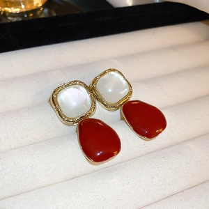 Detail of red teardrop earrings with gold trim and square mother of pearl inlay