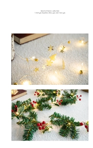 Close-up of golden metal snowflake charms and pine needle garland with red berries LED lights