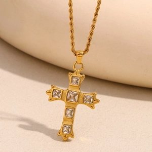 Macro detail of 18K gold cross necklace with square zircons on a textured twist chain