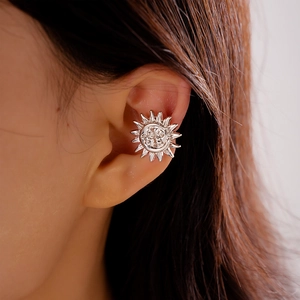Close-up of a silver sun face ear cuff in metallic celestial design worn on the ear