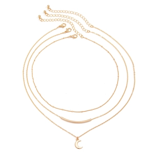Detailed close-up of layered gold necklace with tube bar and moon pendant on white background