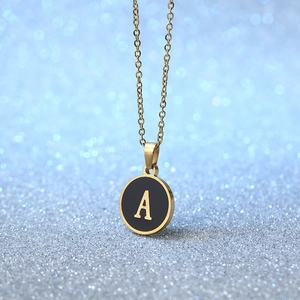 Minimalist gold necklace with black enamel round pendant featuring golden letter A