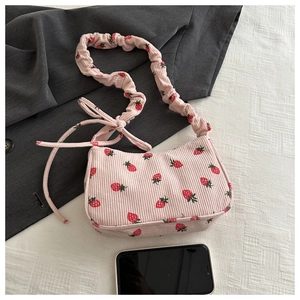 Detailed close-up of pink corduroy shoulder bag featuring strawberry print and ruched strap