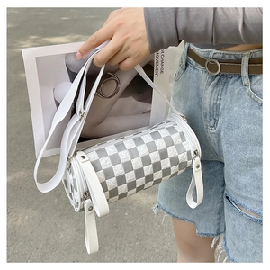 Detail of checkered cylinder bag featuring a white wide strap and silver metal hardware