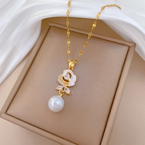 Detail of flower pendant with white zircon inlay and hanging pearl on gold chain
