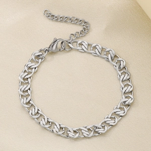 Détail d'un bracelet gourmette NK en acier argenté avec chaîne réglable sur fond de soie