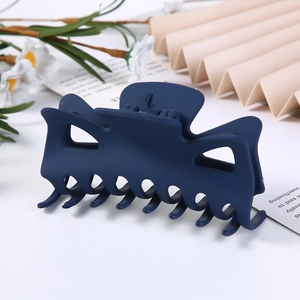 Close-up of a large dark blue geometric hair claw clip on a minimalist floral background