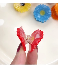 Close-up of a small red heart-shaped acetate hair claw clip held by hand for scale