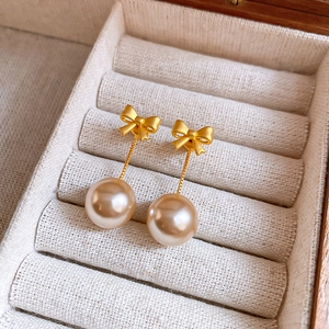 Elegant gold bow earrings with white pearls displayed in a premium jewelry gift box