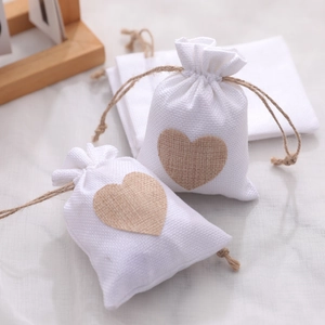 Two white linen Christmas gift bags with brown heart patches and drawstring closure