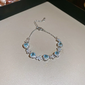 Detailed view of silver bracelet featuring heart-shaped blue stones and zircon floral accents