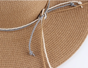 Close-up of brown straw sun hat featuring a three-color braided rope decorative trim