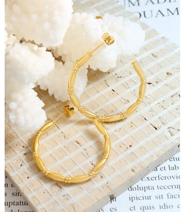 Detail view of gold-plated titanium C-shaped earrings with bamboo texture on stone