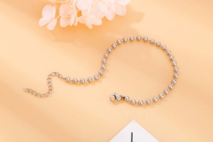 Silver bead bracelet with lobster clasp and extender chain on soft orange backdrop