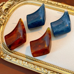 Detailed view of vintage geometric resin earrings in amber and marble blue on a gold tray