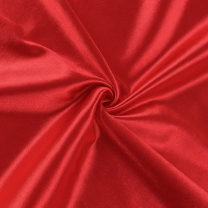 Close-up of red satin fabric with elegant pleated spiral texture and silky shine