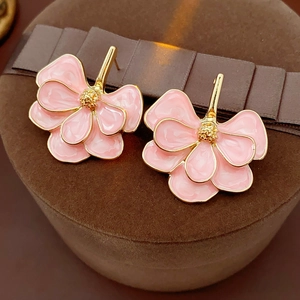 Close-up of vintage floral earrings with pink petals and gold-plated textured edges