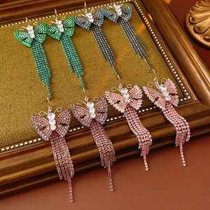 Dettaglio di orecchini con nappe a farfalla in zircone verde, blu e rosa viola