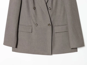 Detail of grey double-breasted blazer showing fabric texture and flap pockets
