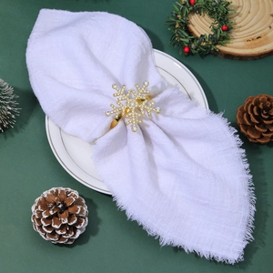 Close-up of golden snowflake napkin ring with rhinestones on a white linen napkin