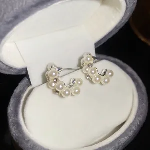Elegant silver pearl hoop earrings with crystal accents on a grey velvet display