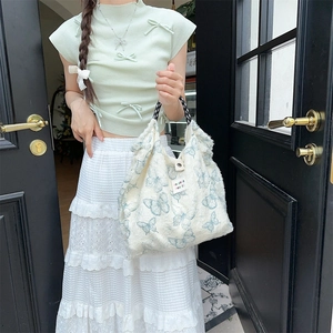 Detail of canvas bag with light blue butterfly patterns and woven handles
