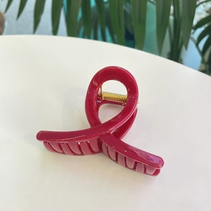 Détail d'une pince à cheveux torsadée rouge vif avec un ressort métallique doré