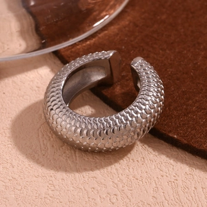 Detailed macro view of silver-tone C-shape earrings with intricate fish scale textures