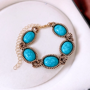 Detail of vintage turquoise resin bracelet in retro gold braided frame on white display