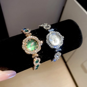 Close-up of luxury diamond-encrusted round watches in rose gold and silver on black velvet