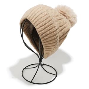 Détail du bonnet en tricot beige avec doublure en polaire épaisse et pompon en fourrure