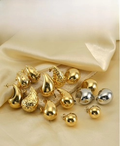 Detail of 18K gold teardrop earrings and stud sets on silk and stone background