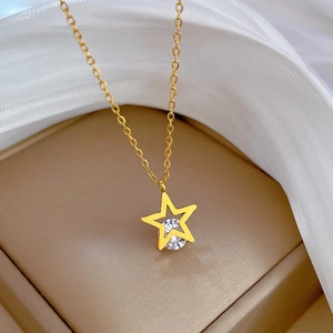 Detailed close-up of golden hollow star necklace with a central zircon on silk background