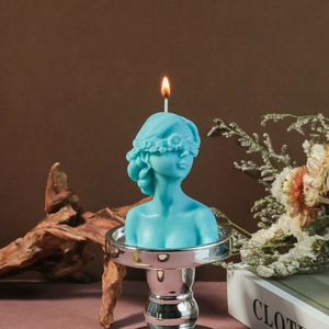Artistic blindfolded woman bust candle with floral blindfold lit on silver base