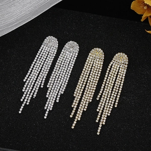 Close-up detail of long rhinestone tassel earrings with silver and gold plating