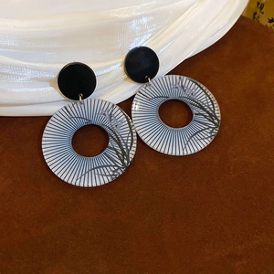Detail of vintage round dangle earrings with black botanical leaf patterns and stripes