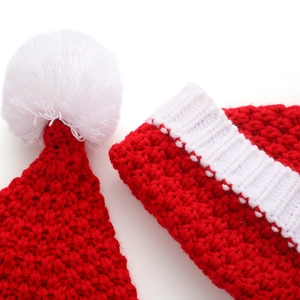Knitted red and white Santa hat with fluffy pompom detail for Christmas holiday season