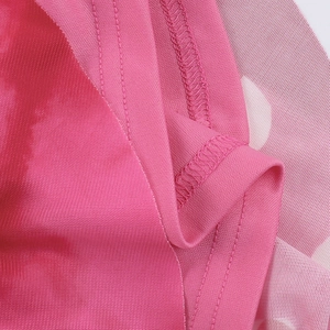 Gros plan du tissu en maille rose montrant la texture fine et les volants de la robe bustier