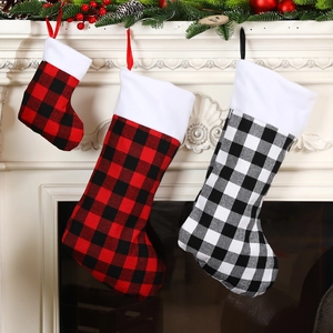 Red and black buffalo plaid Christmas stockings with white faux fur trim on a cozy fireplace