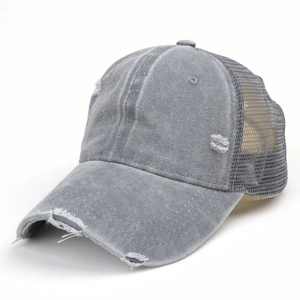 Detailed close-up of distressed denim cap showing vintage holes and breathable mesh back