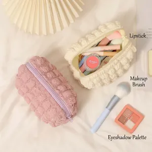 Quilted puffy makeup bag in cream and pink colors shown with cosmetics and magazines