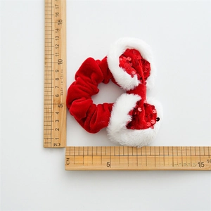 Detailed view of red velvet scrunchie with white plush trim and red sequins decoration