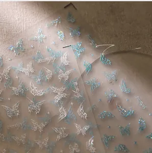 Détail macro de stickers pour ongles papillon laser 3D en argent et bleu clair brillant