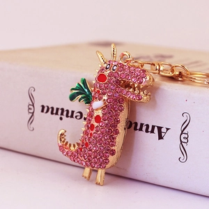 Porte-clés dragon rose en strass avec fermoir doré sur un livre de collection