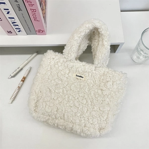Detail of white sherpa fleece tote bag with a soft plush texture and woven brand label
