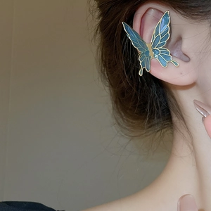 Close-up of blue butterfly ear cuff with gold trim on model's ear for stylish look