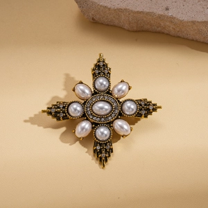 Macro detail of vintage cross brooch with pearls and crystals on golden metal texture