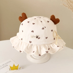 Detailed view of beige baby sun hat with heart print, rabbit badge, and chin ties