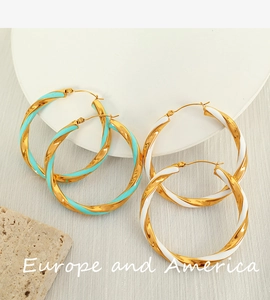 Detailed shot of large twisted hoop earrings in gold with blue and white enamel inlay